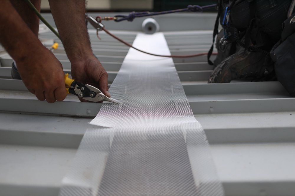 A Man is Cutting a Piece of Tape With a Pair of Pliers — Goulburn Roofing In Mittagong, NSW