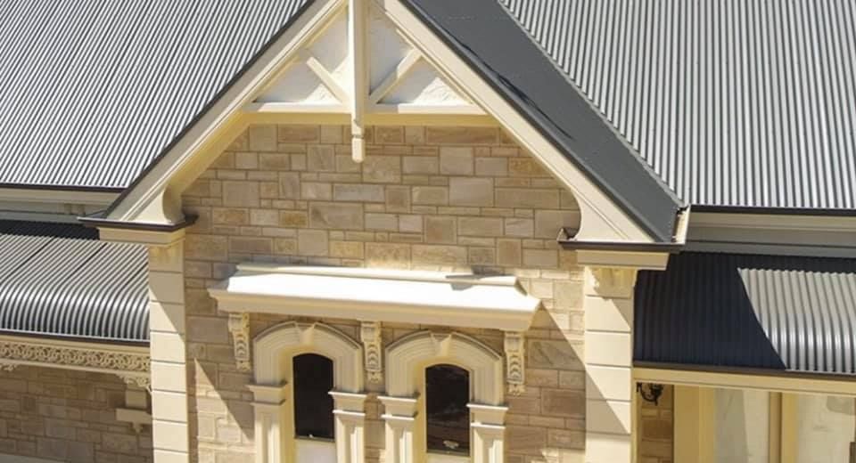 A Large Brick Building With a Black Roof and a Porch — Goulburn Roofing In Bowral, NSW