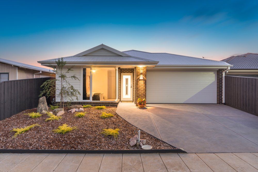 A White House With a Driveway and a Fence in Front of It — Goulburn Roofing In Goulburn, NSW