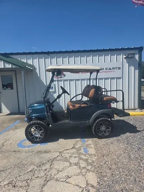 Blue golf cart with custom wheels, parked in front of a business with 