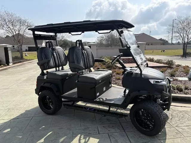White six-seat golf cart with tan seats and black roof, shown on a plain white background