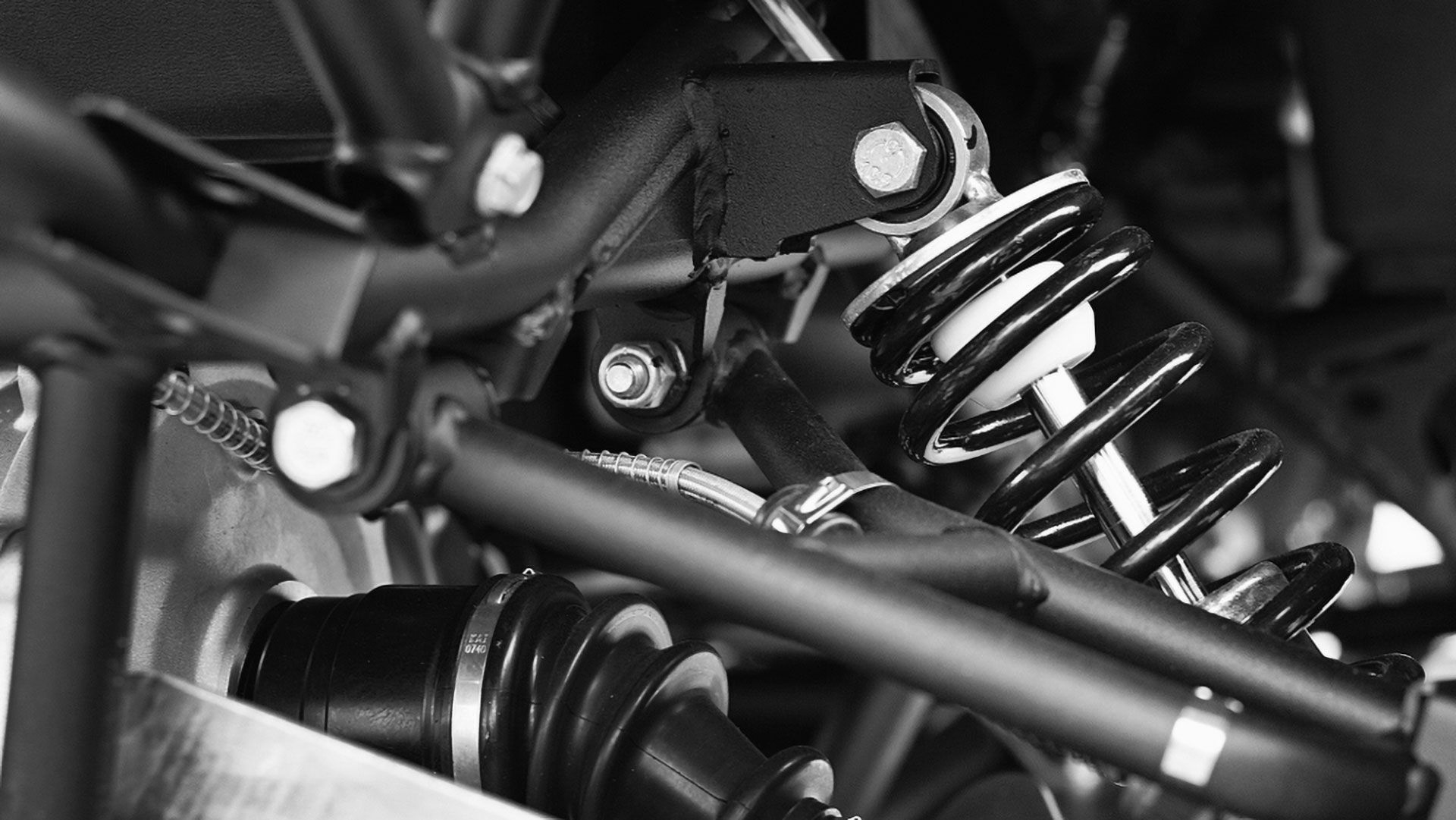Close-up of a black ATV frame with a visible coil-over shock absorber and a drive axle assembly.