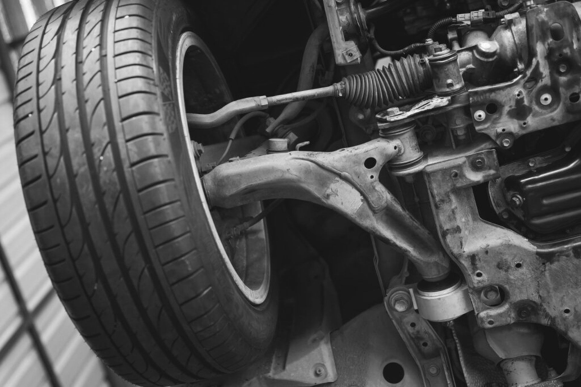 The underside of a car showcasing the wheel, steering linkage, and suspension control arm assembly.