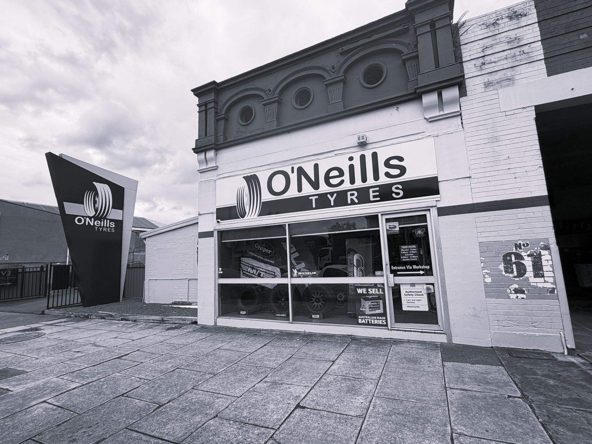 The O'Neills Tyres storefront, a building with an ornamental facade, stands beside a tall, dark, angled sign.