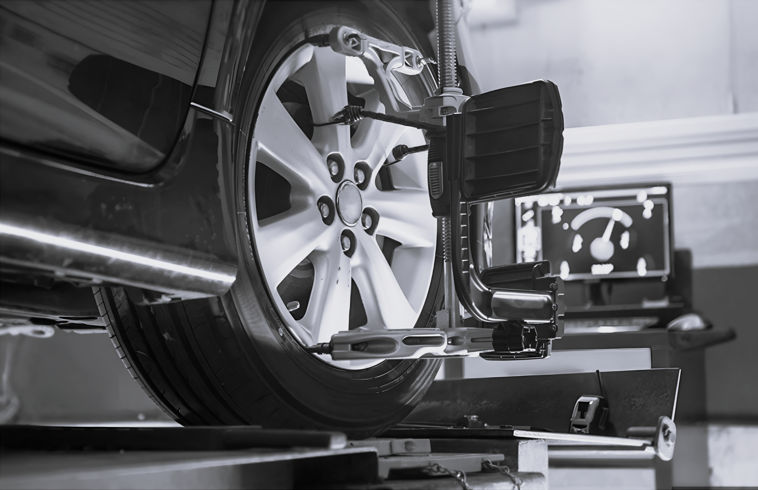 A car wheel mounted on a professional alignment rack with sensor equipment attached for diagnostic testing.
