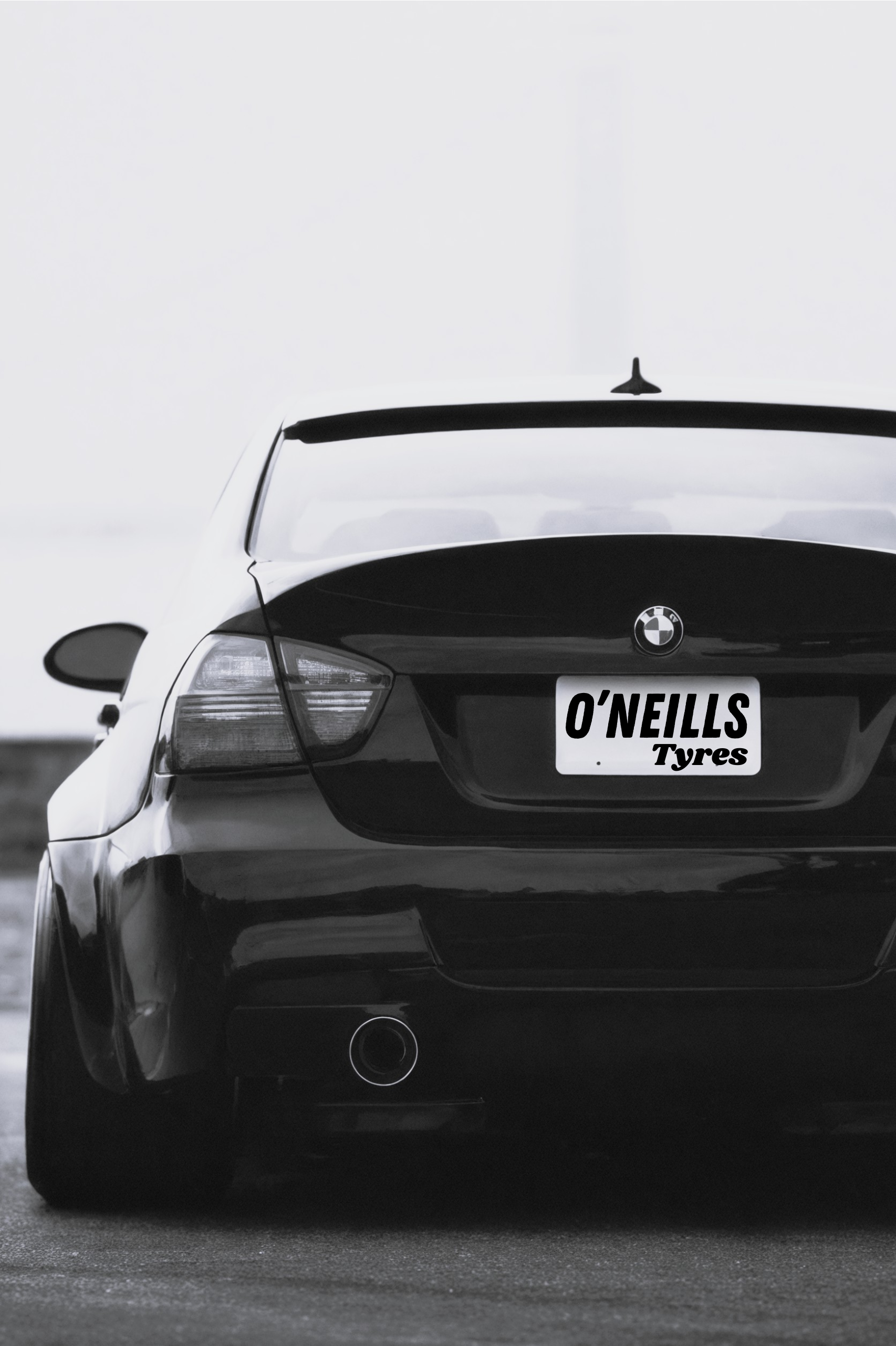 A black BMW sedan seen from the rear, featuring a custom license plate that reads 