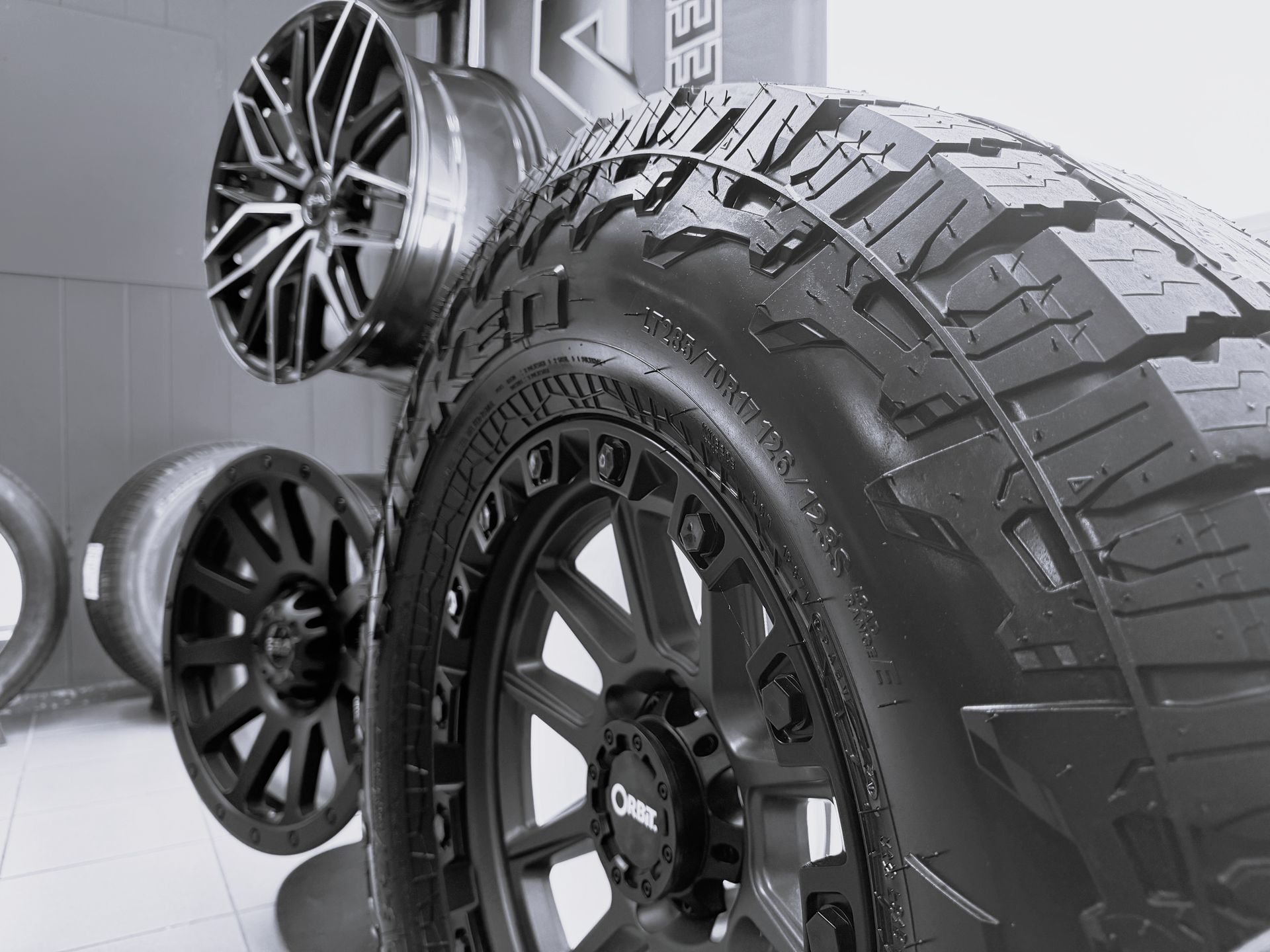 Display of various black car wheels and tires mounted on racks in a shop.