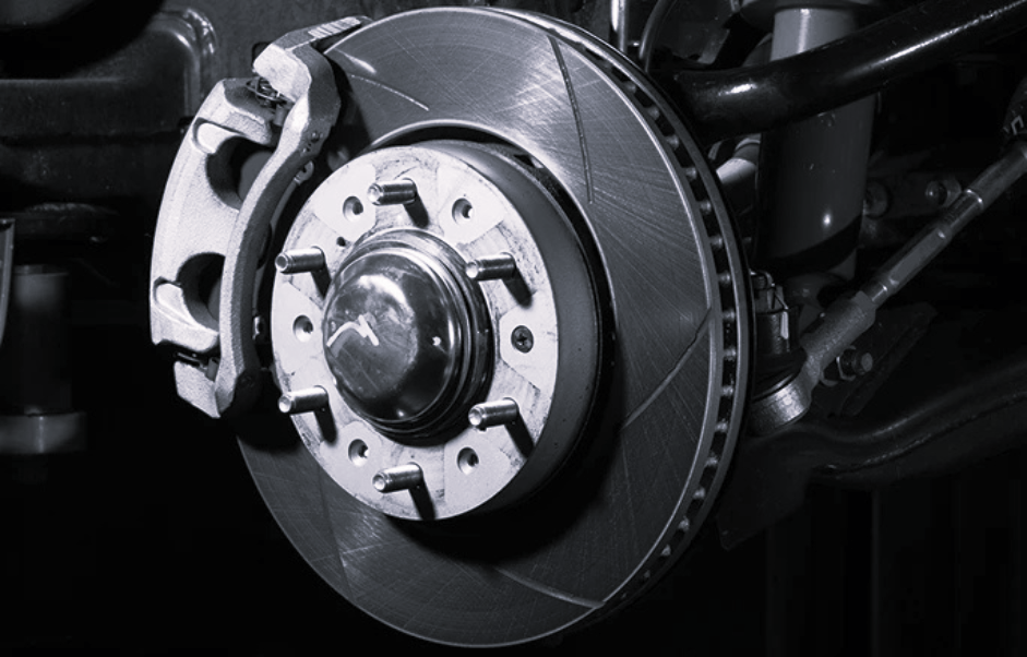 Close-up of a vehicle's disc brake system, showing the rotor, brake caliper, and wheel hub assembly in a studio setting.