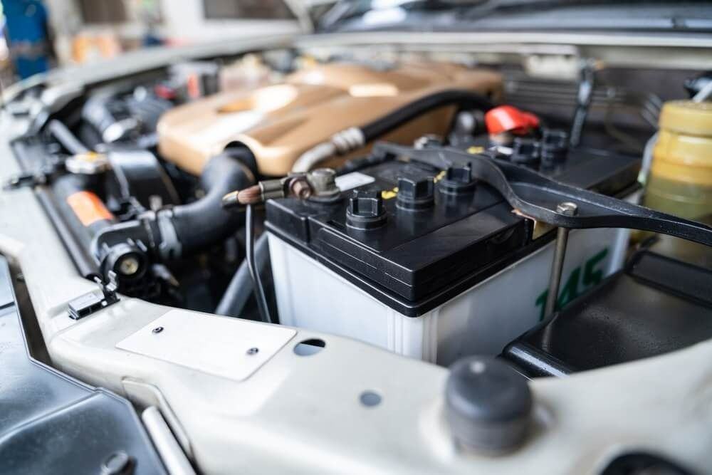 A close-up view of a car battery installed inside a vehicle's open engine bay.