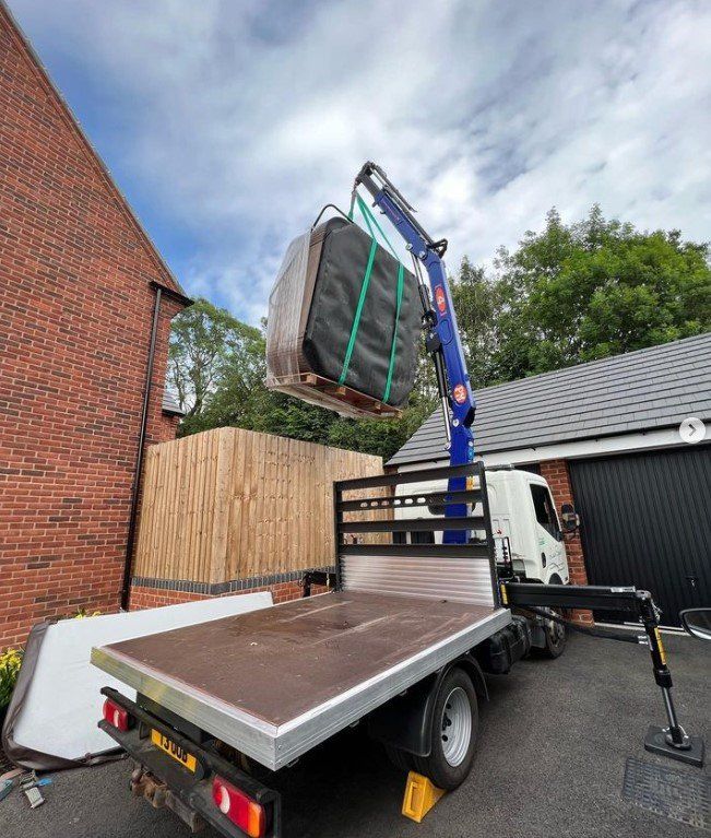 A crane is lifting a large object from the back of a truck.