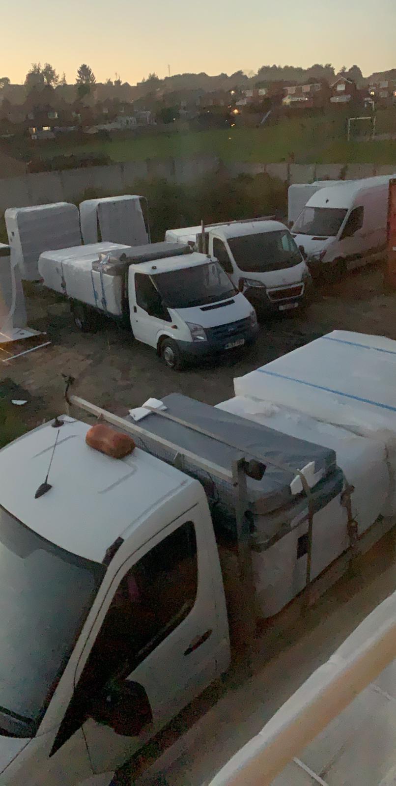 A row of white vans parked in a parking lot.