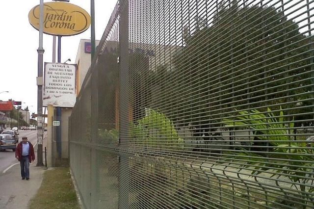 Un hombre pasa junto a un cartel que dice jardin corona
