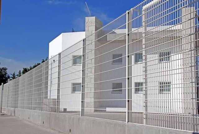 Una valla rodea un edificio con un cielo azul de fondo.