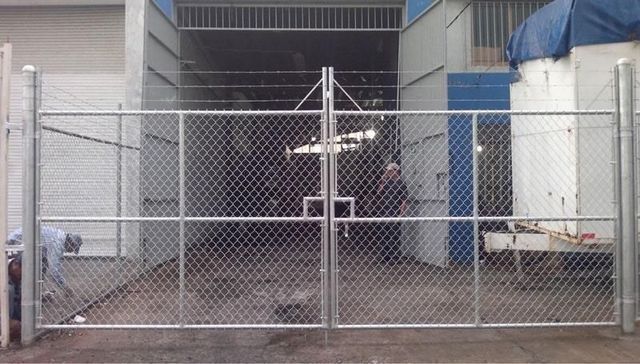 Un hombre está trabajando en una valla metálica frente a un edificio.