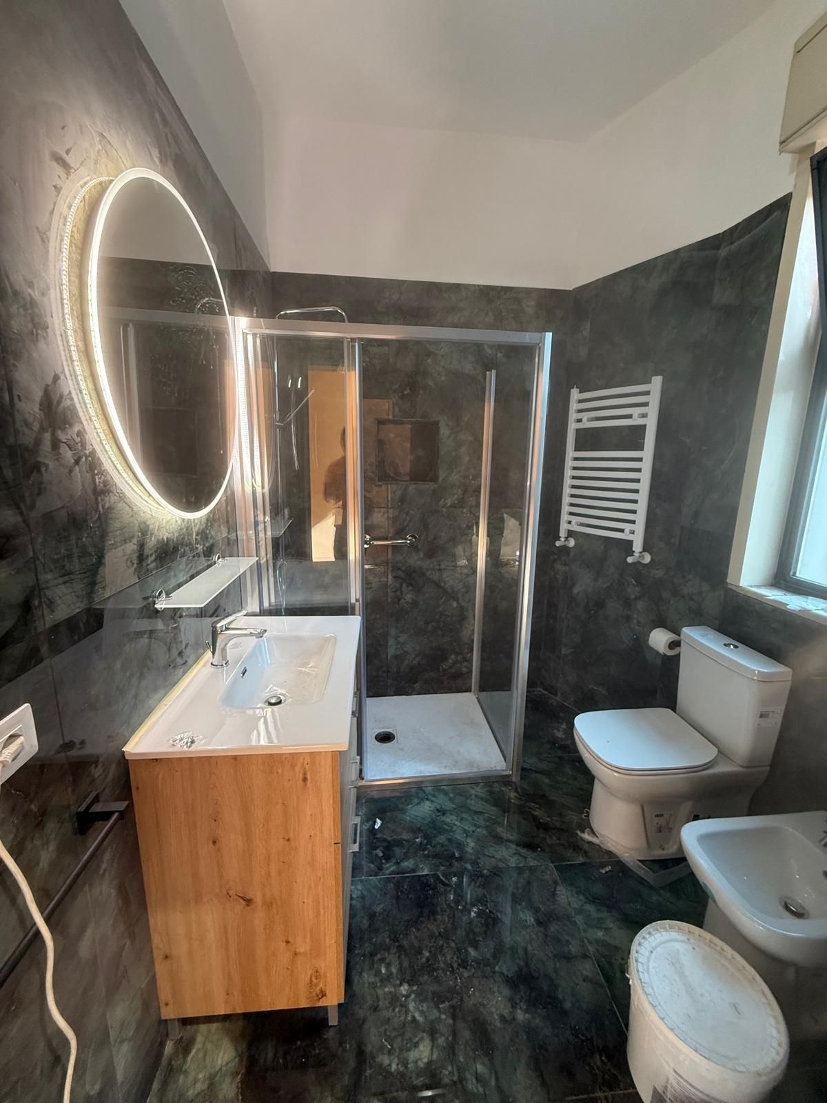 Una piattaforma aerea rossa e bianca con un braccio esteso, posizionata su una strada accanto a un edificio.