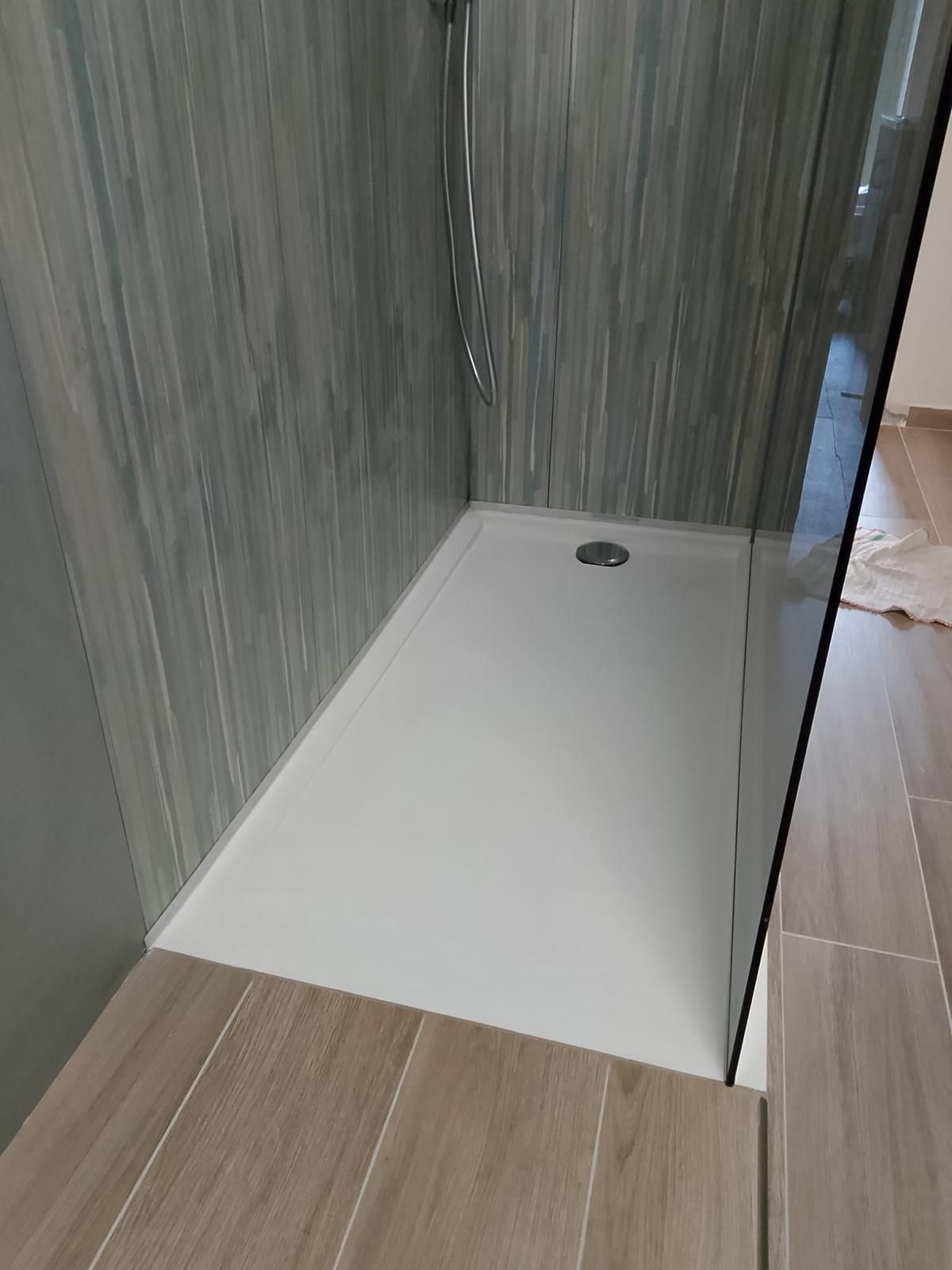 Due operai installano pannelli di legno attorno a una porta in una stanza con pareti grigie testurizzate.