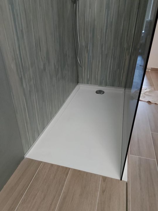 Due operai installano pannelli di legno attorno a una porta in una stanza con pareti grigie testurizzate.