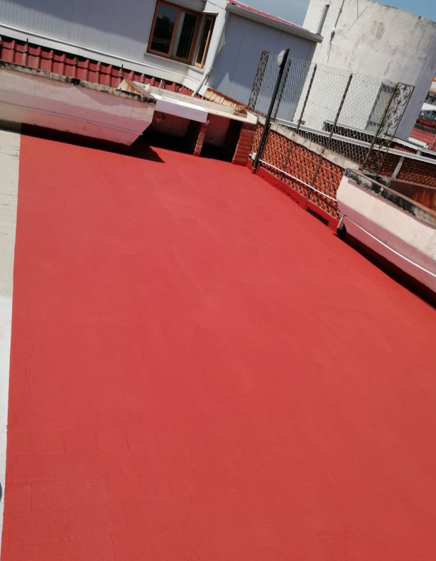 Tetto dipinto di rosso con ringhiera in metallo e edificio adiacente.