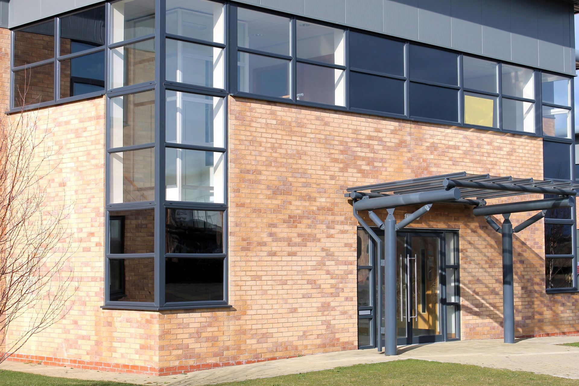 Edificio in mattoni con ampie finestre e ingresso coperto.