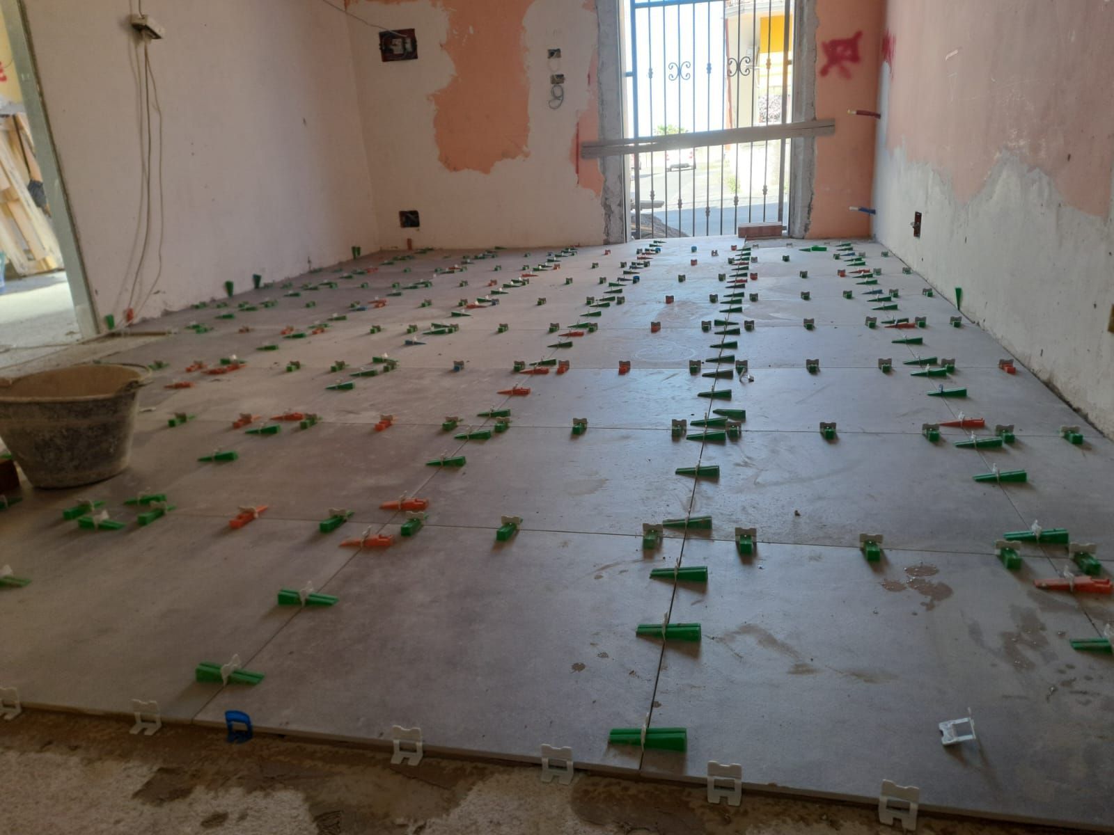 Piastrelle installate sul pavimento, con i componenti del sistema di livellamento in posizione.