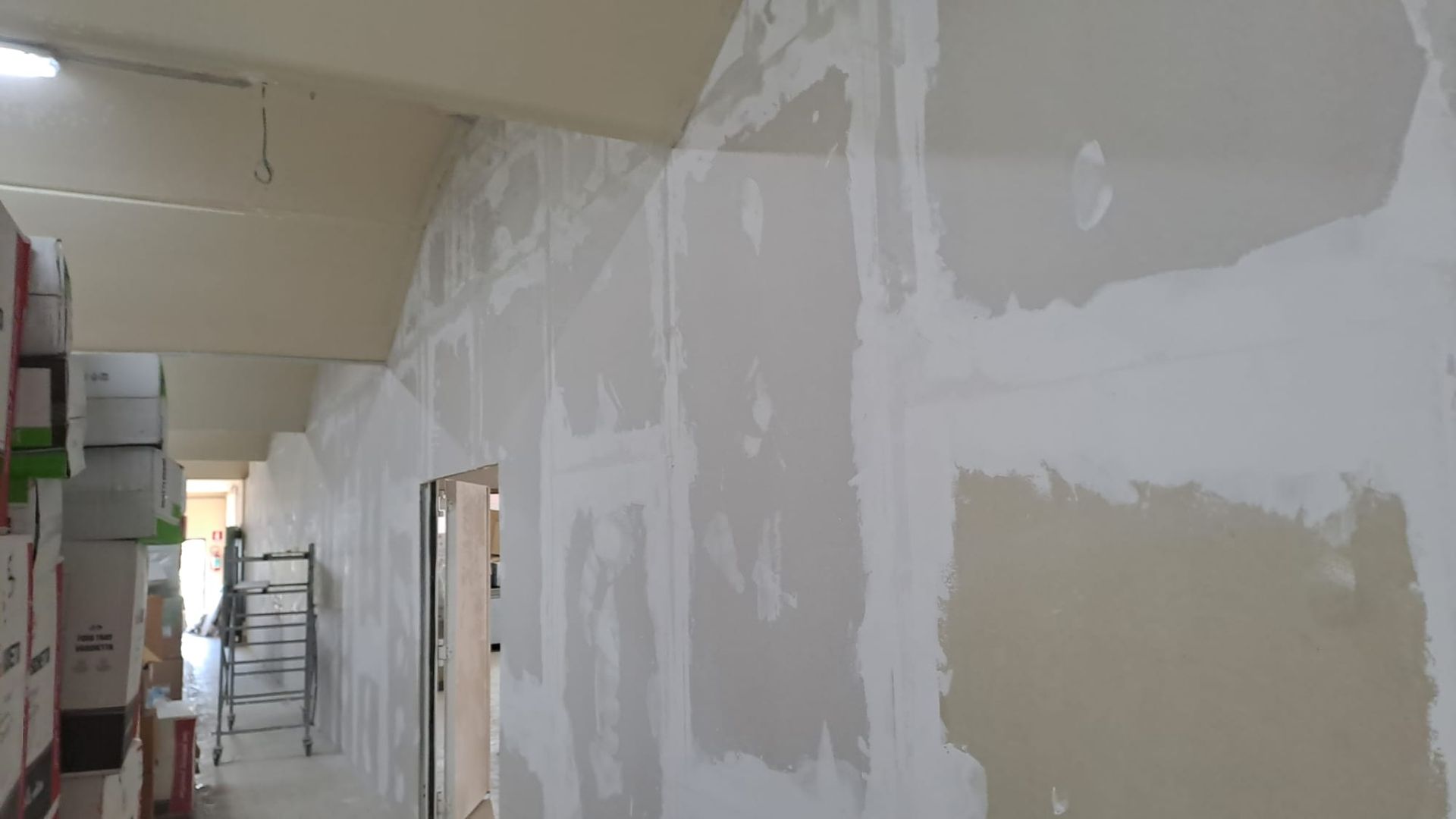 Installazione del muro a secco in corso; corridoio interno con pareti non finite.