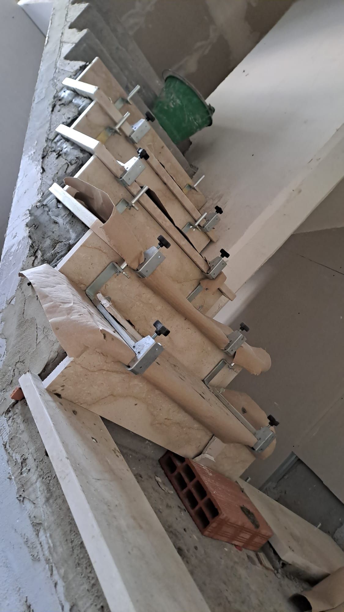 Cassaforma in legno per la costruzione di scale, fissata a un muro, con un secchio verde visibile.