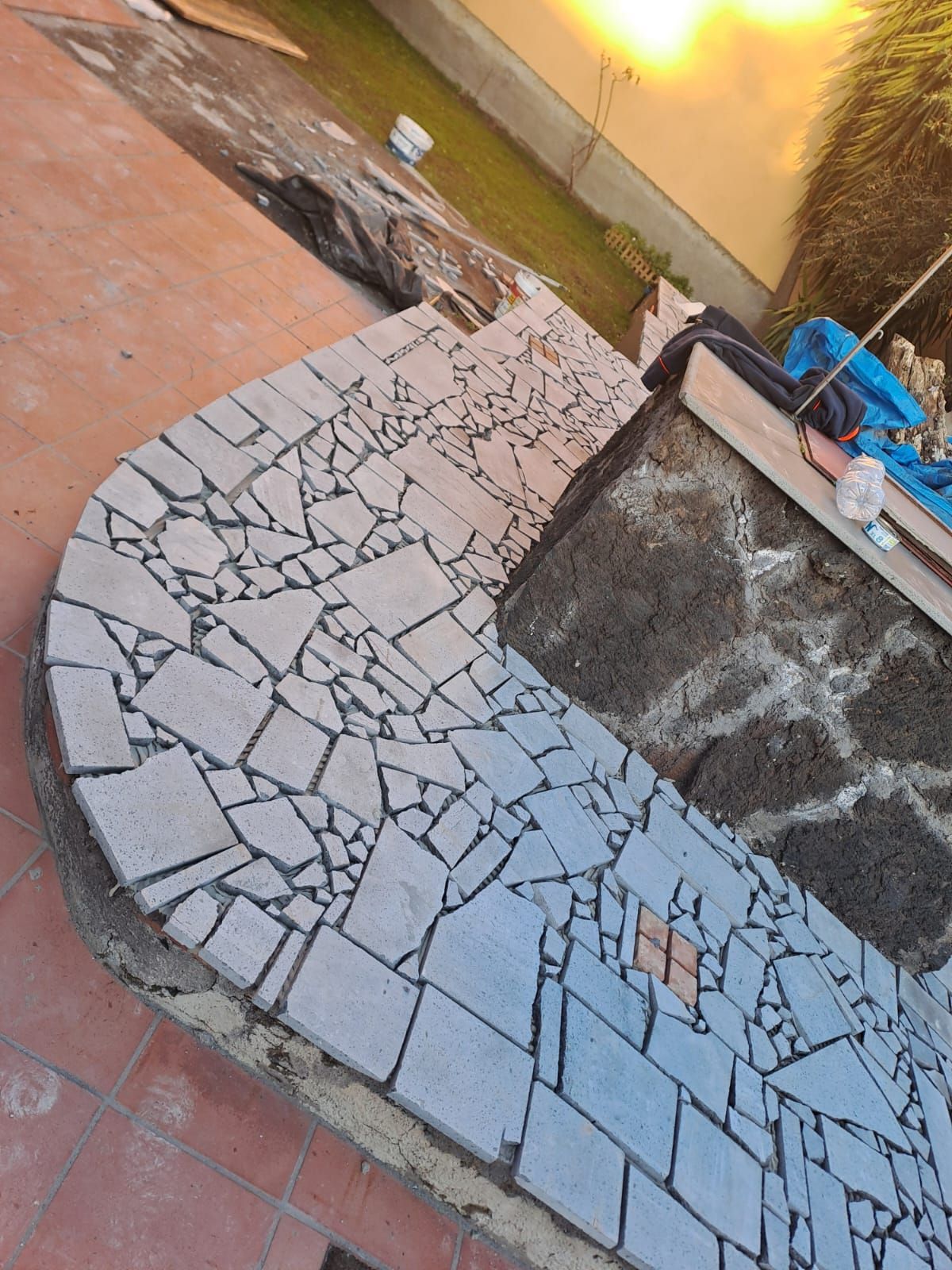 Percorso piastrellato con bordo curvo, realizzato con piastrelle di forma irregolare e di colore chiaro.