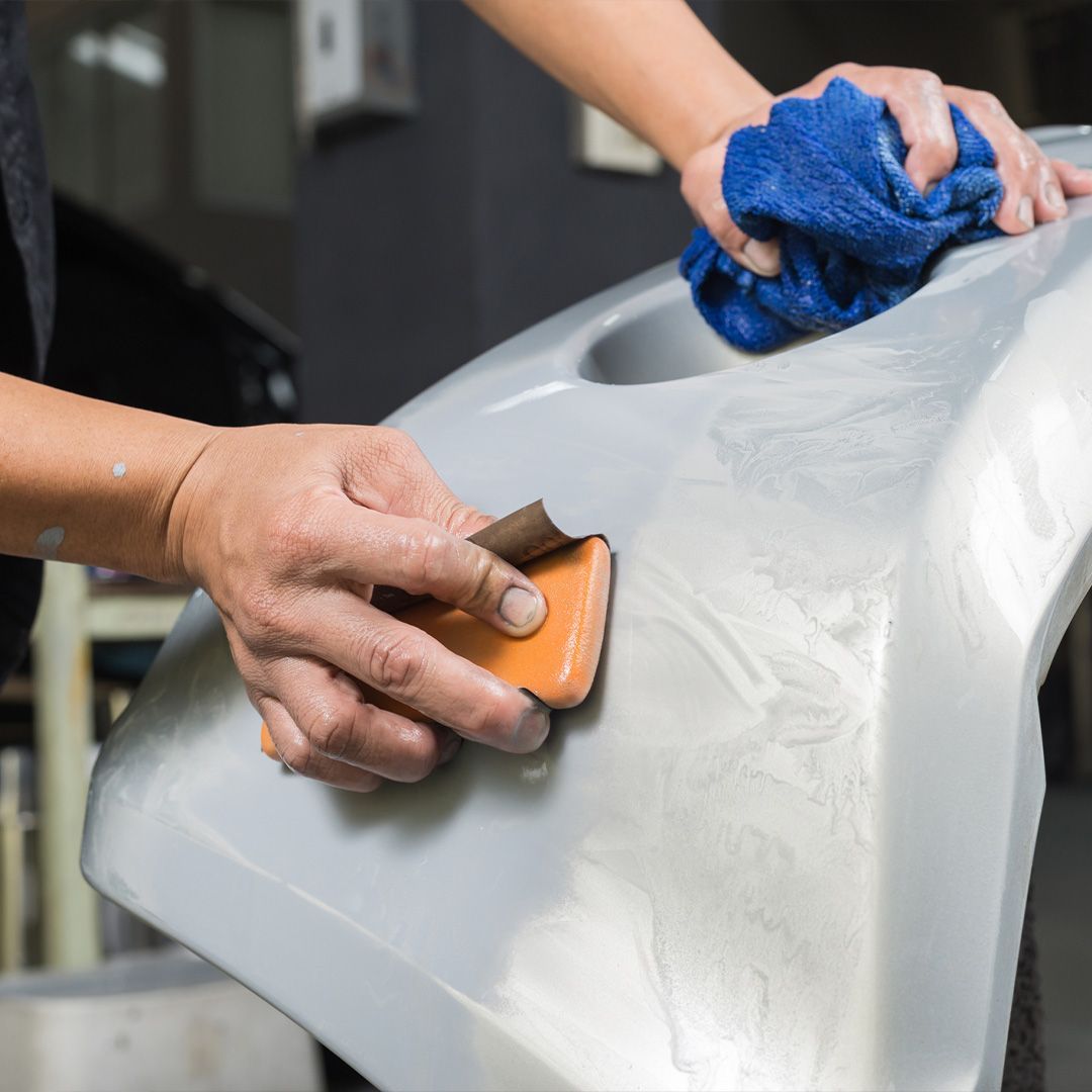 a person is sanding a bumper with a sanding block and a towel .