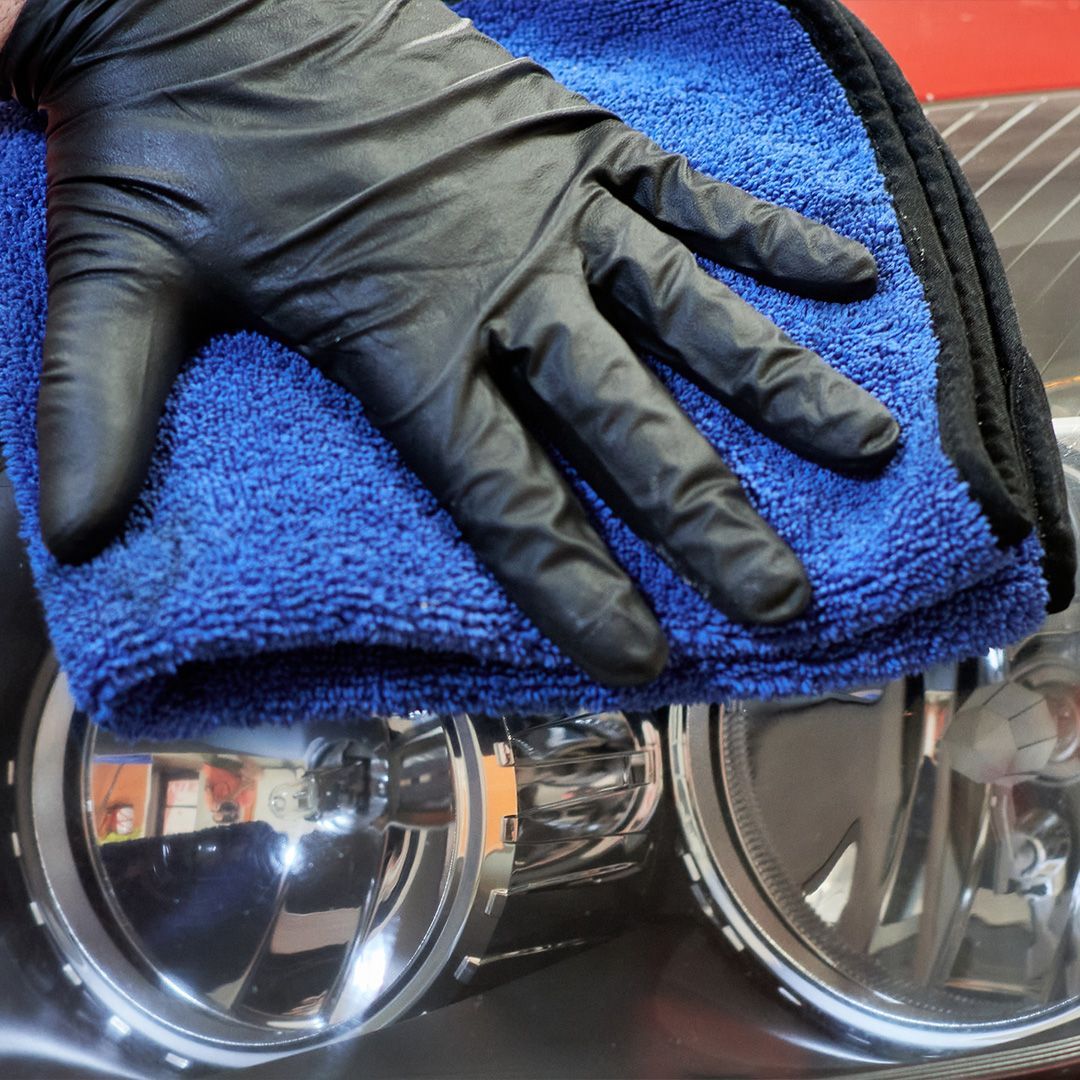 a person wearing black gloves is holding a blue towel
