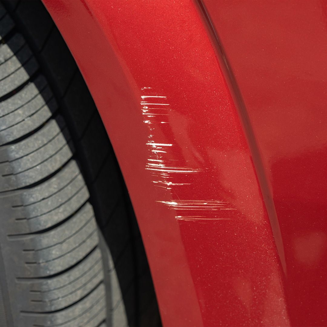 a red car has a scratch on the fender