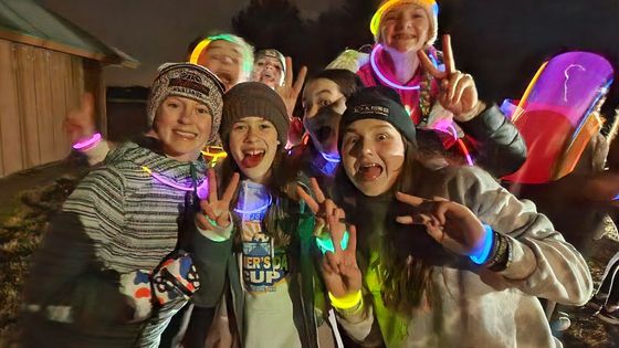 A group of children are posing for a picture with glow in the dark bracelets.