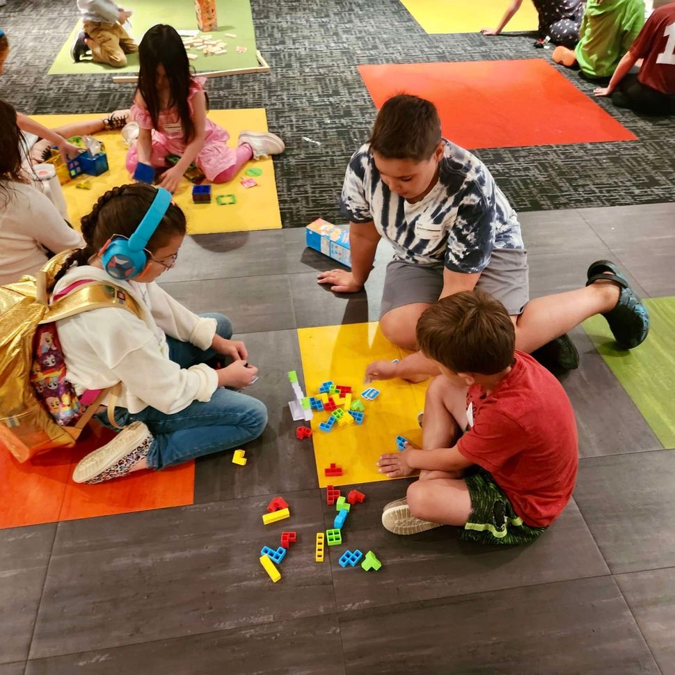 A group of children are playing with lego blocks on the floor