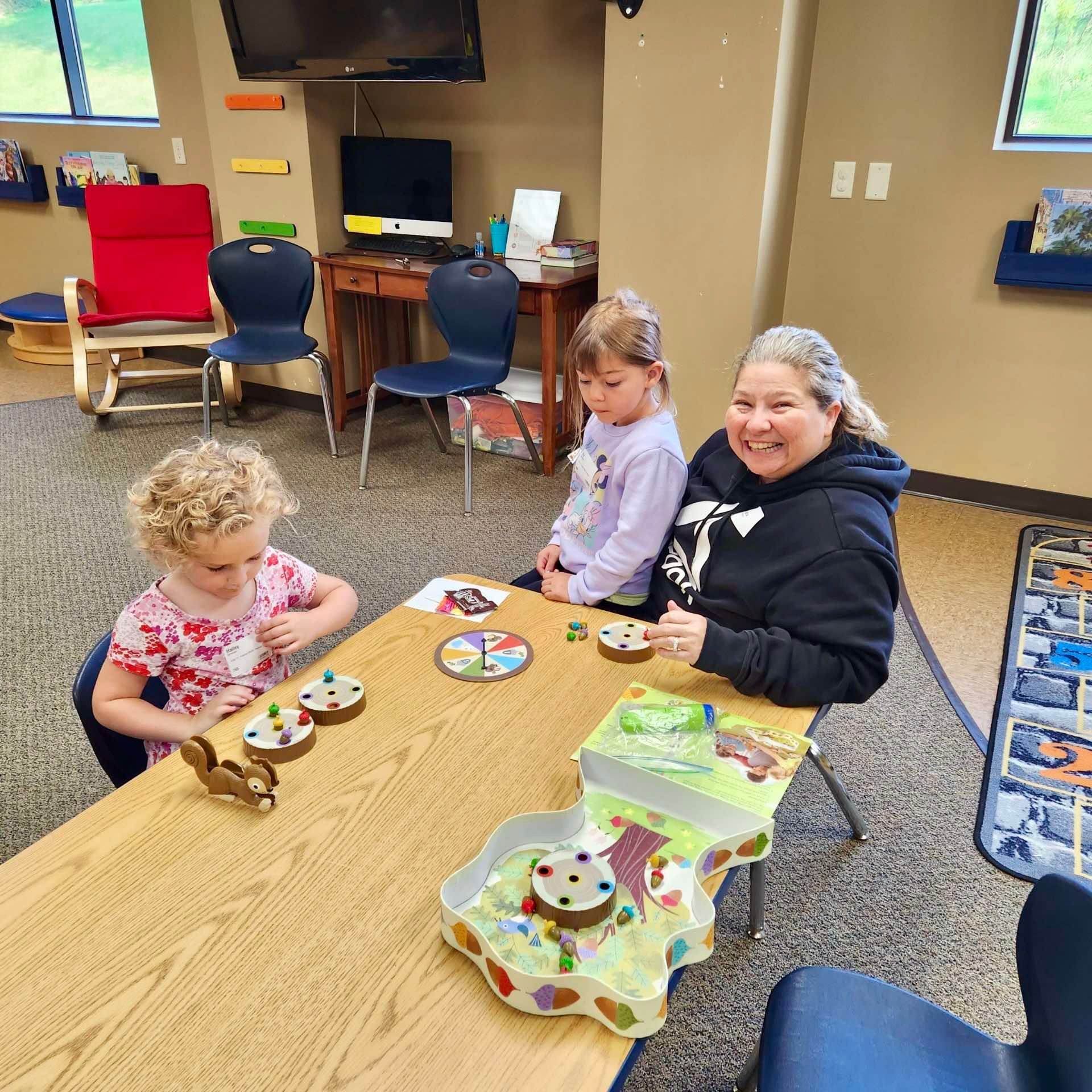 A woman is sitting at a table with two children