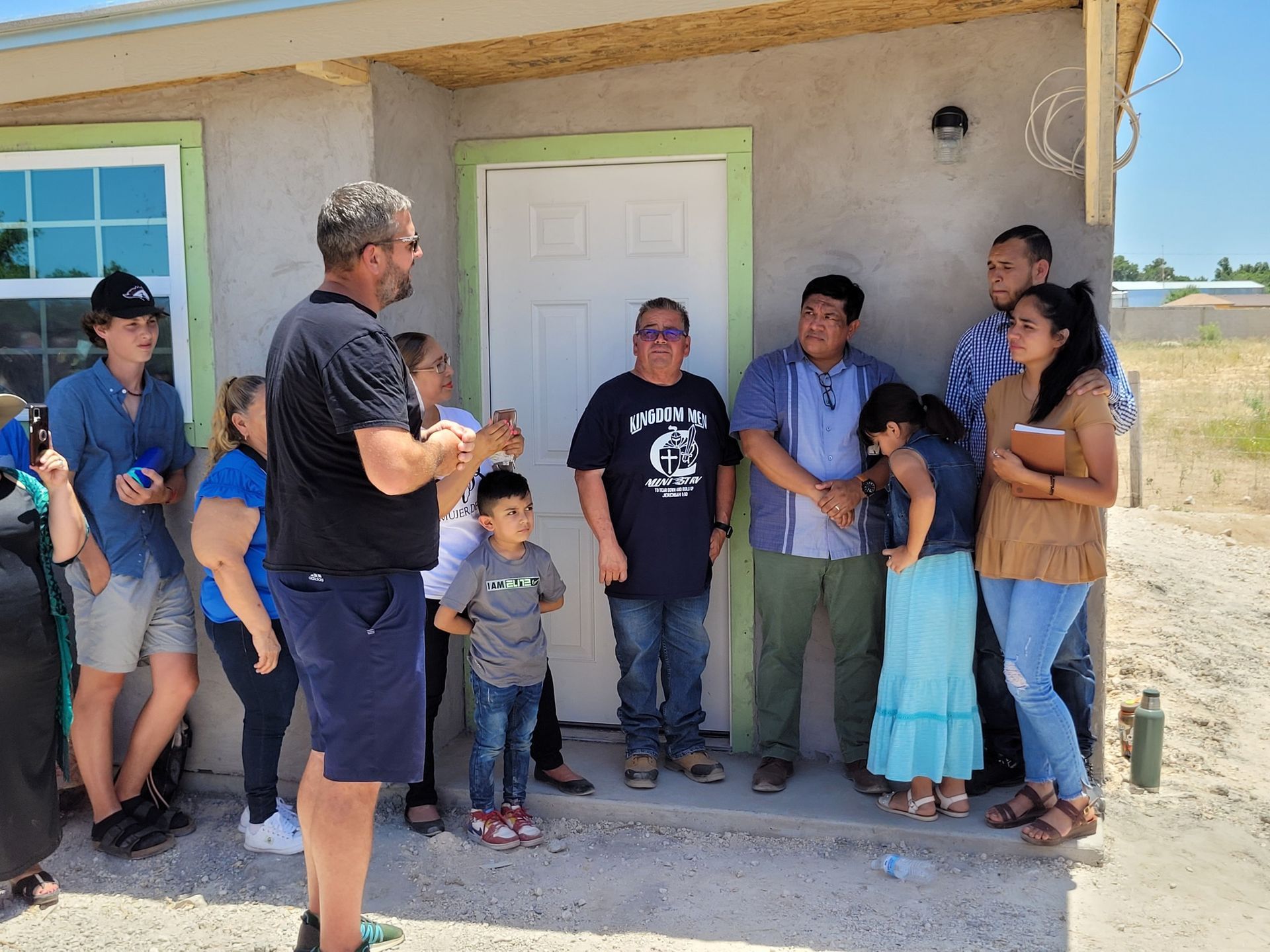 A group of people are standing outside of a house.