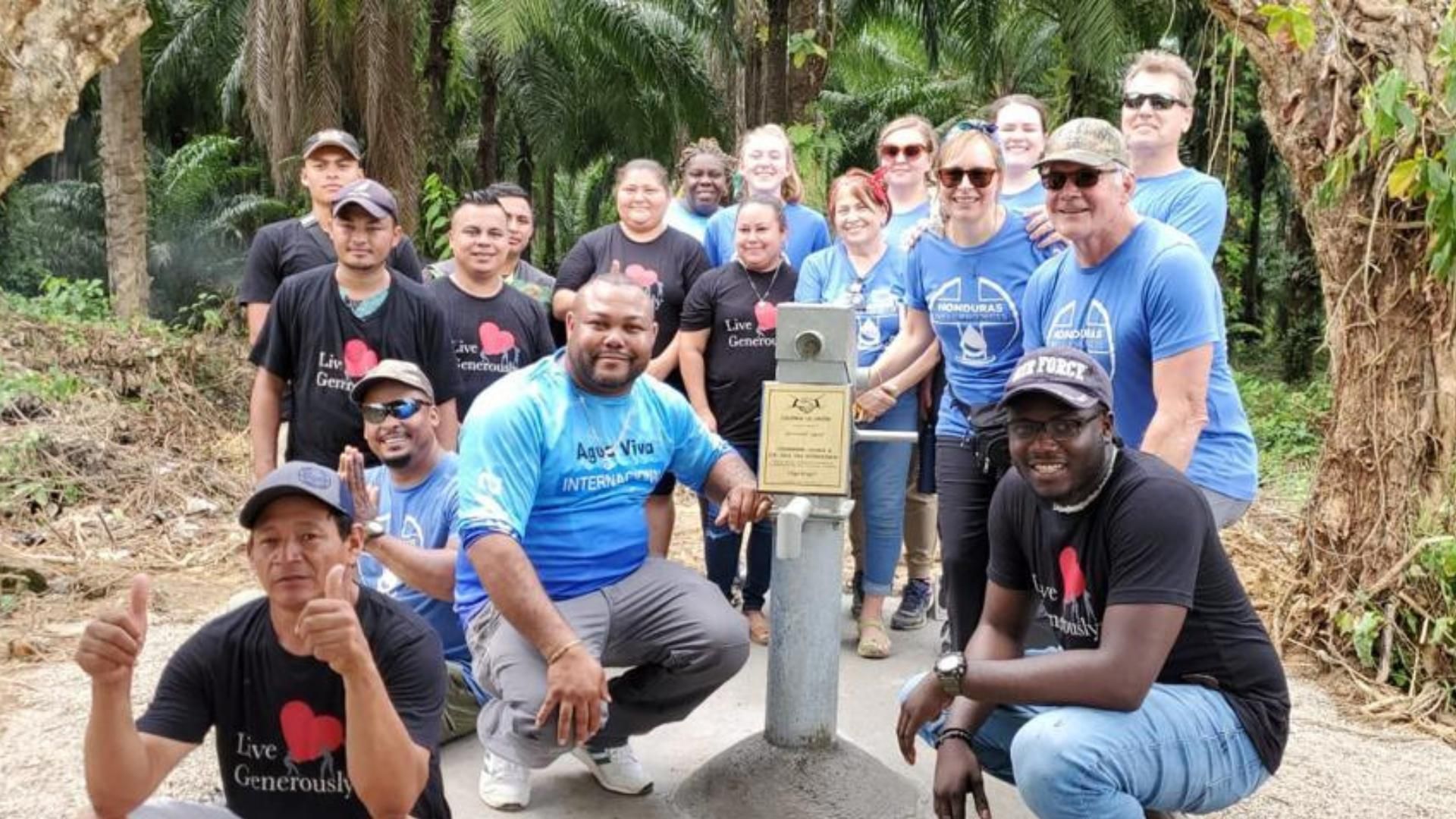 A group of people are posing for a picture in front of a water pump.