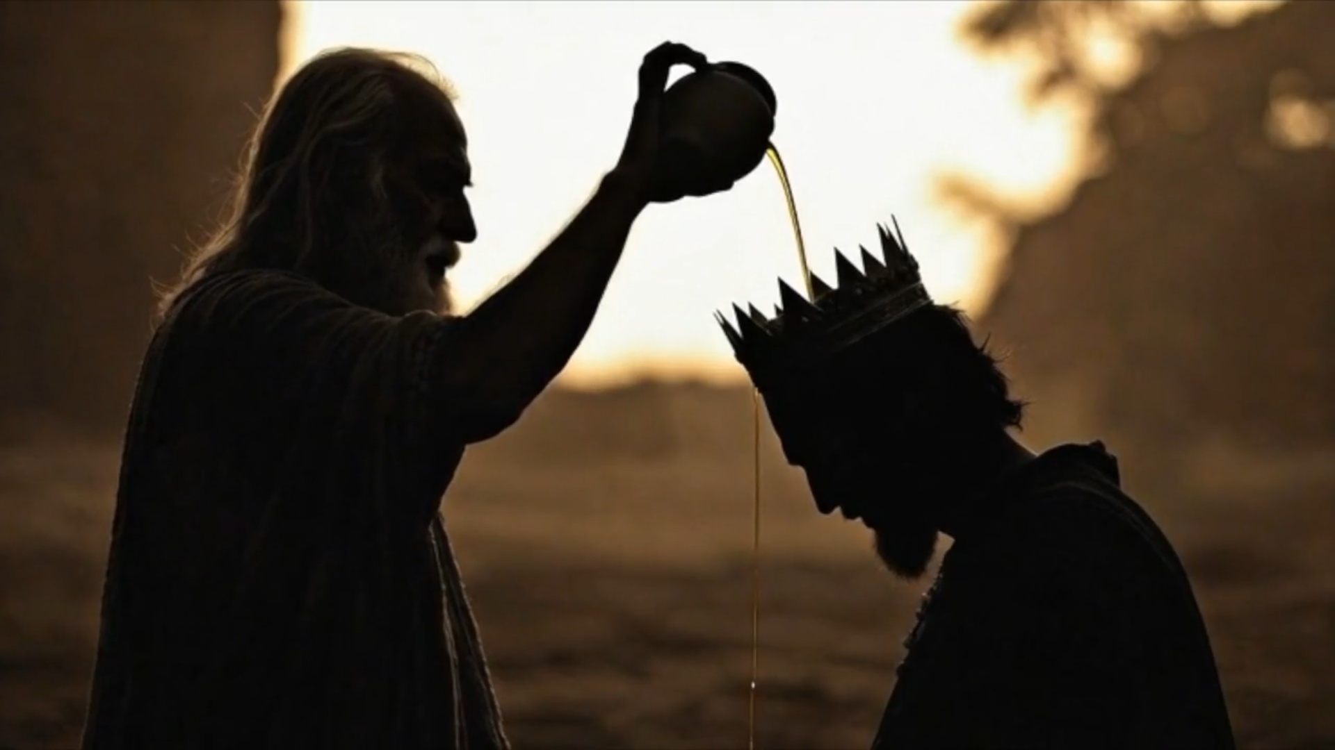 A silhouette of an older figure pouring oil from a vessel onto the head of a person wearing a crown.