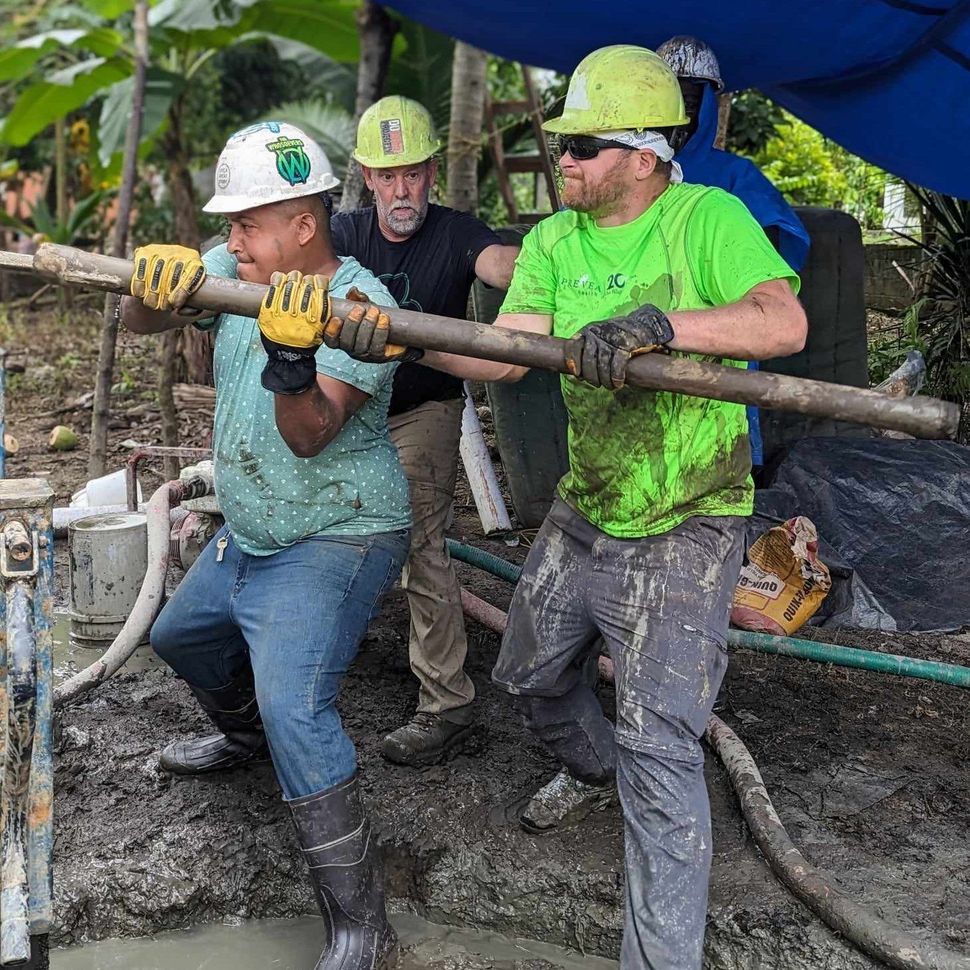 A group of construction workers are working on a water well.