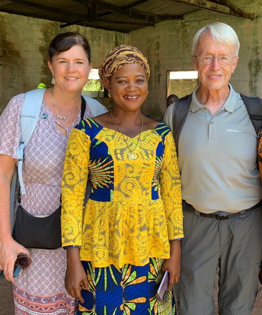 A woman in a yellow and blue dress is posing for a picture with two men