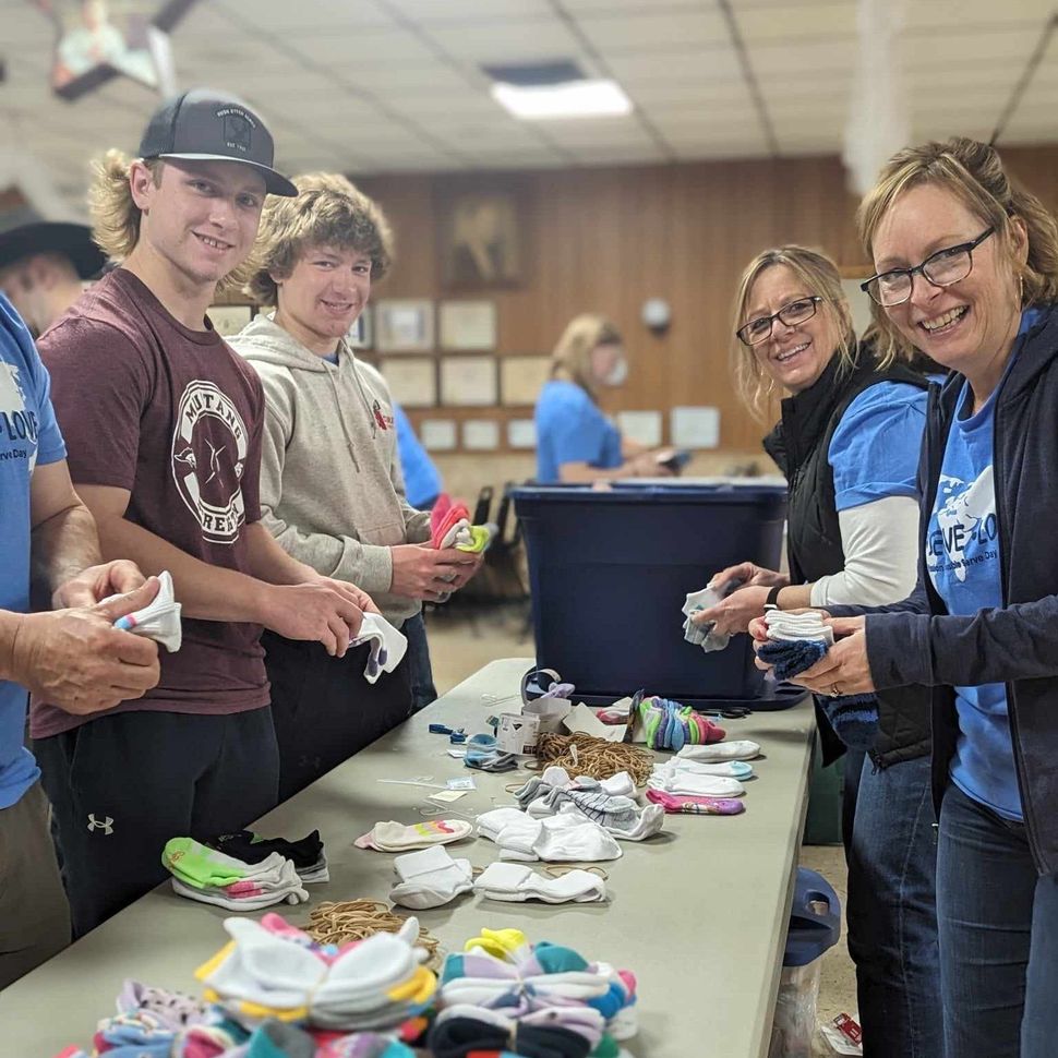 A group of people are standing around a table filled with clothes.