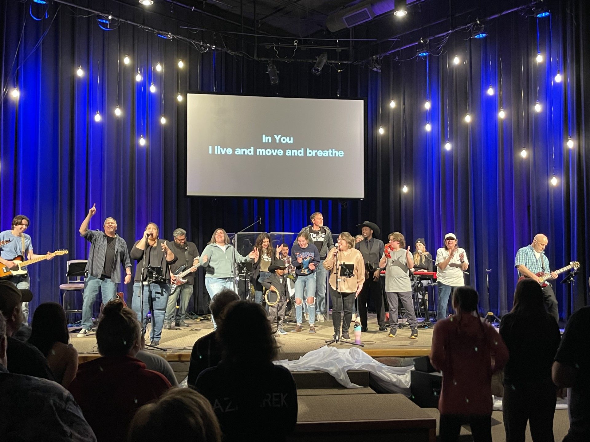 A group of people are standing on a stage in front of a large screen.