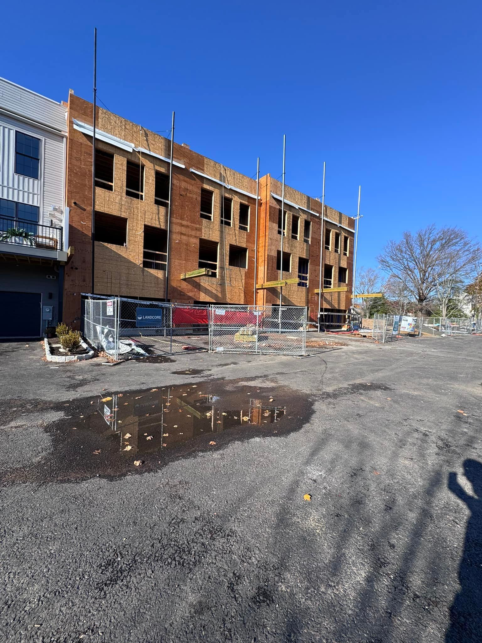 Construction site with brick building, blue sky, and gravel lot.