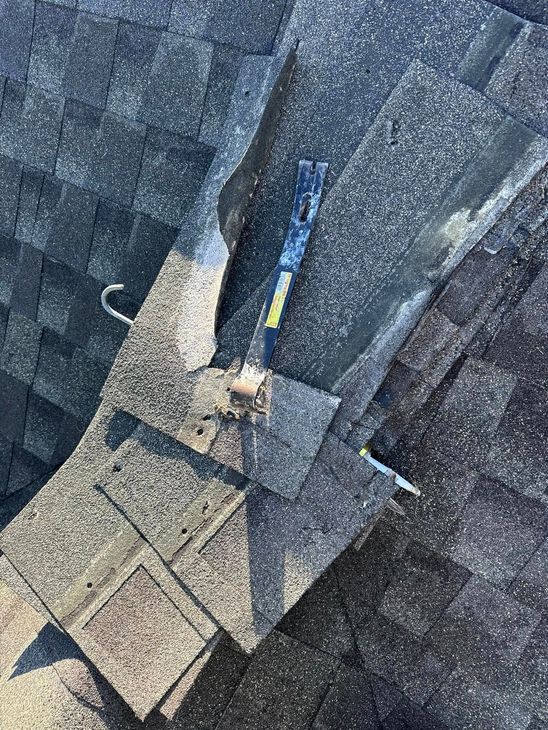 Rooftop with shingles; crowbar, hook and fastener. Granular surface and shadows.