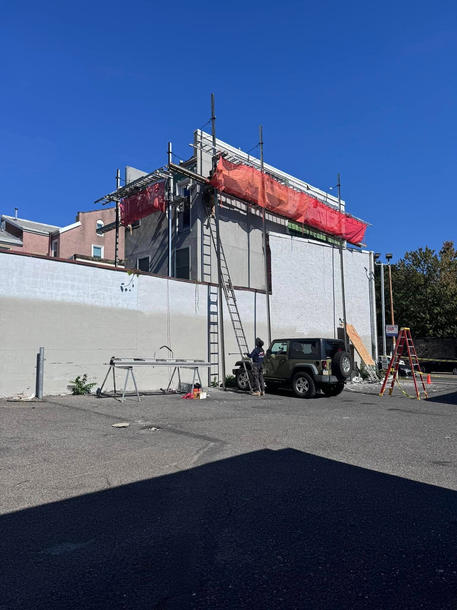 Building under construction with scaffolding and a Jeep in front.