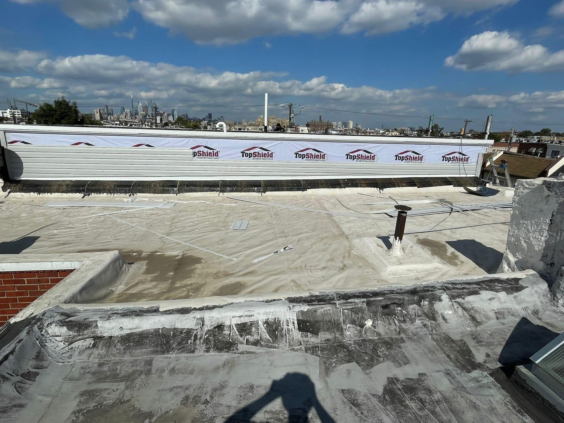 Rooftop view with a long white banner and city skyline. Cloudy sky.