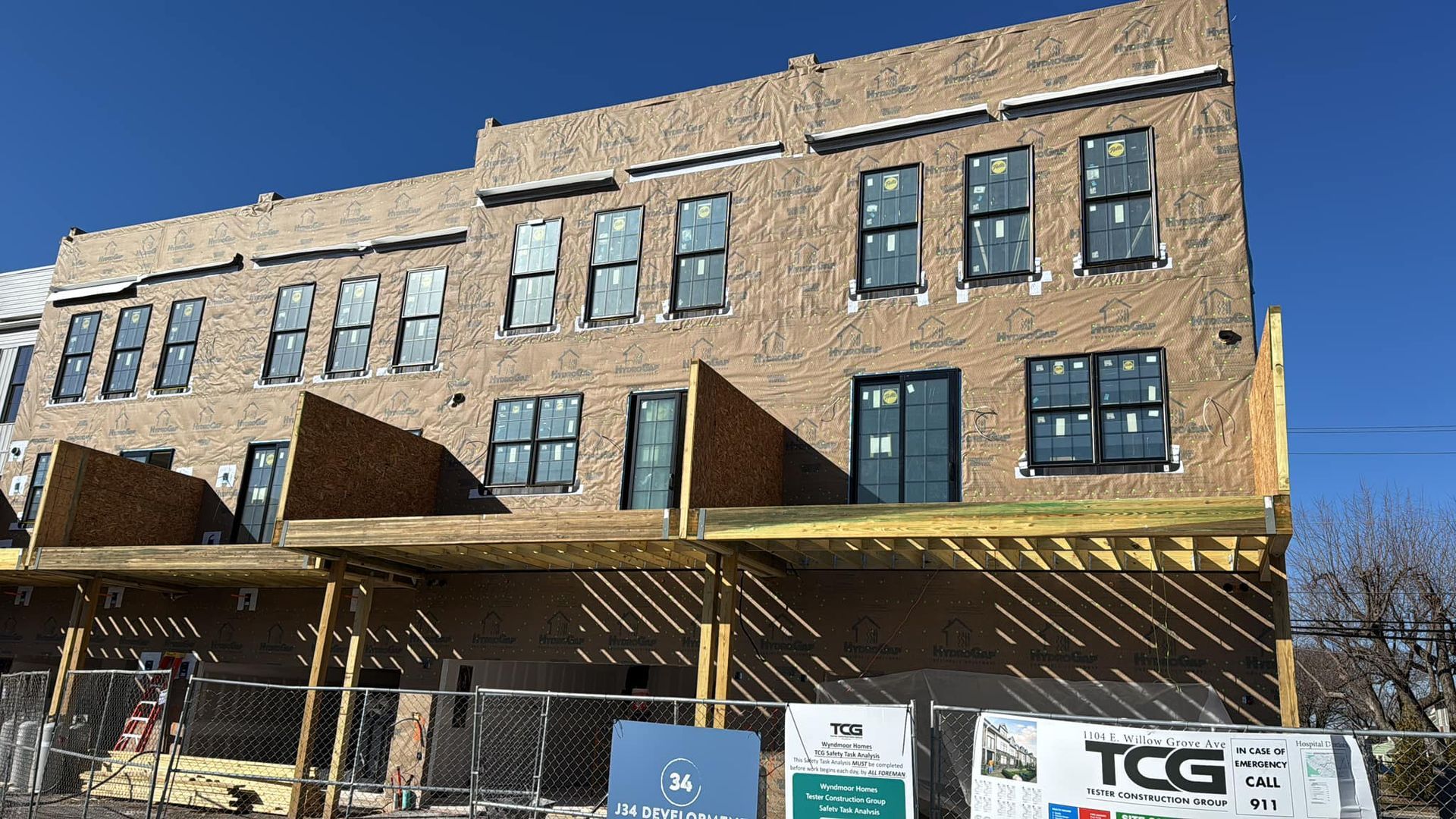 Multi-story brick building under construction with unfinished balconies and a clear blue sky.