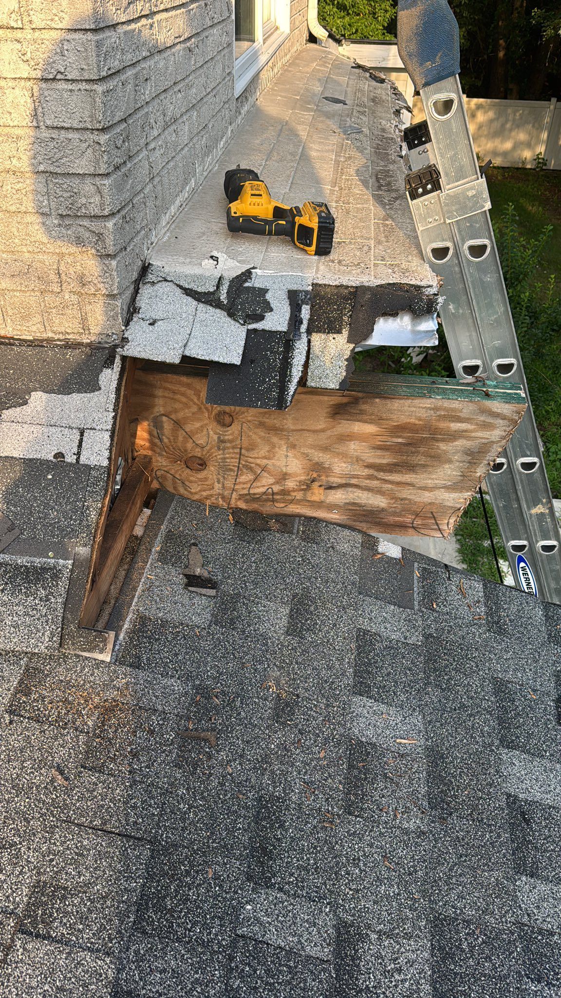 Damaged roof section with exposed wood; a drill is on the surface.