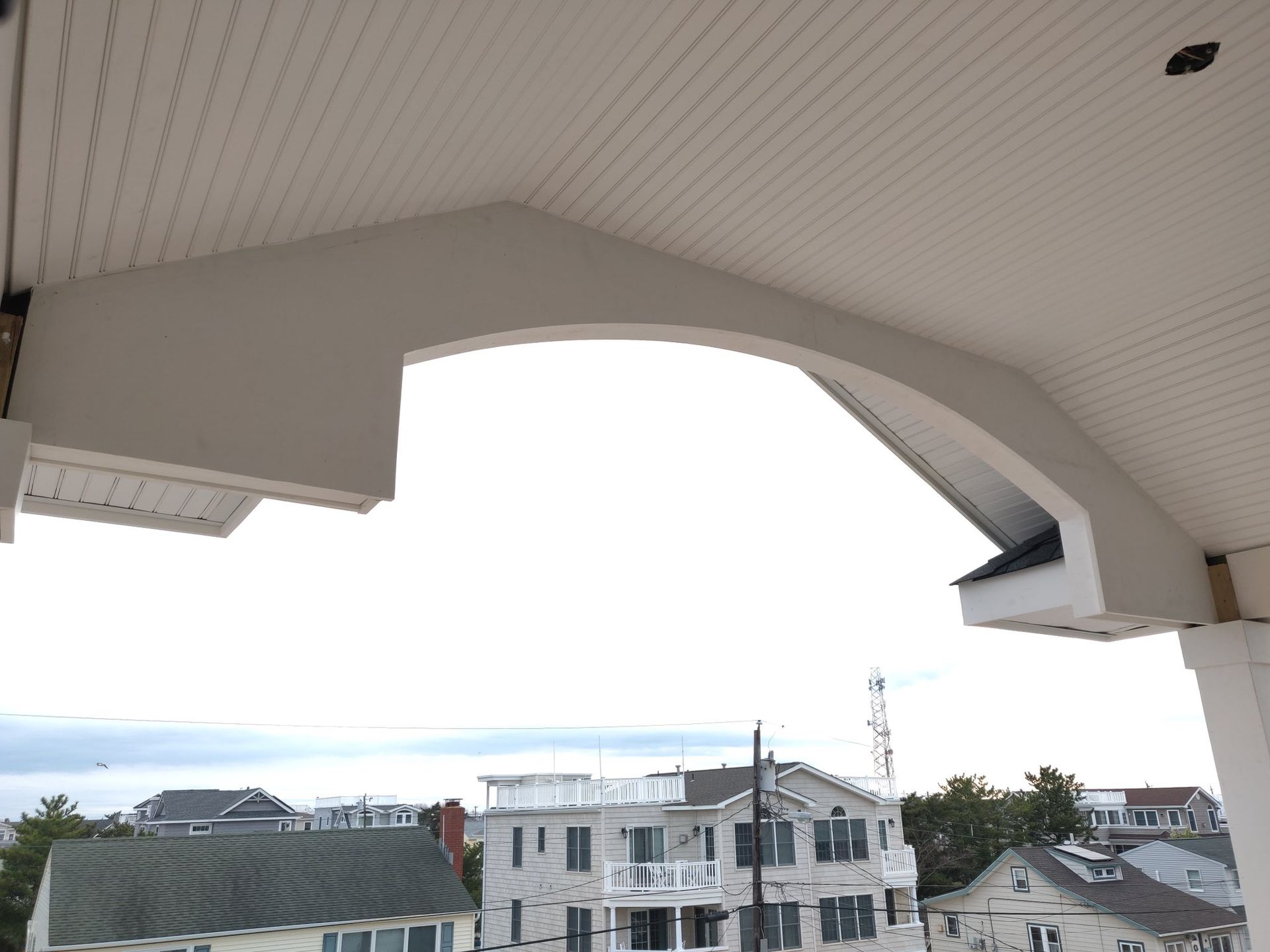 White architectural support with an arched opening, against a cloudy sky.