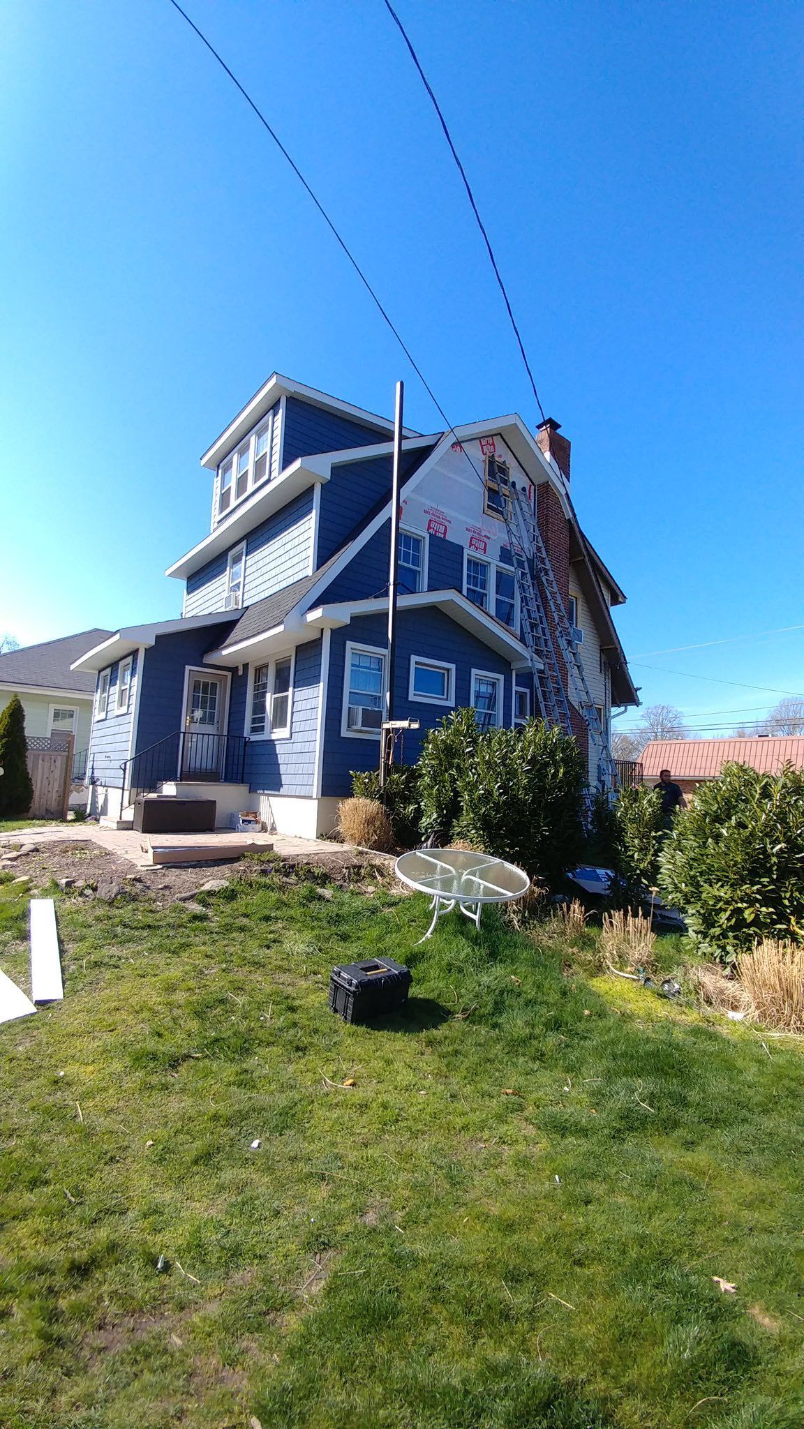 Blue house with antenna against a sunny sky, lawn in the foreground.