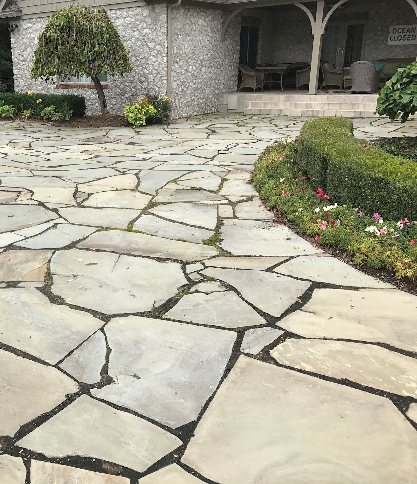 A stone walkway leading to a house with a porch.