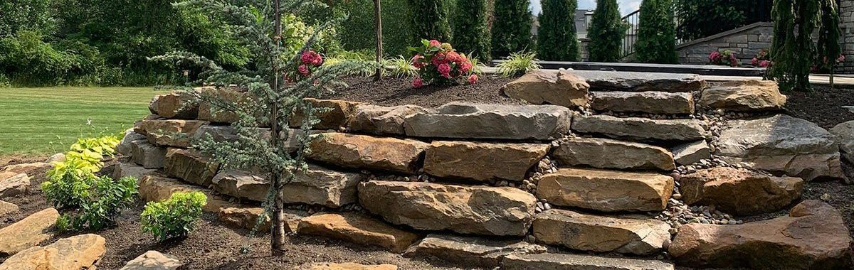 A stone wall with stairs leading up to it in a garden.